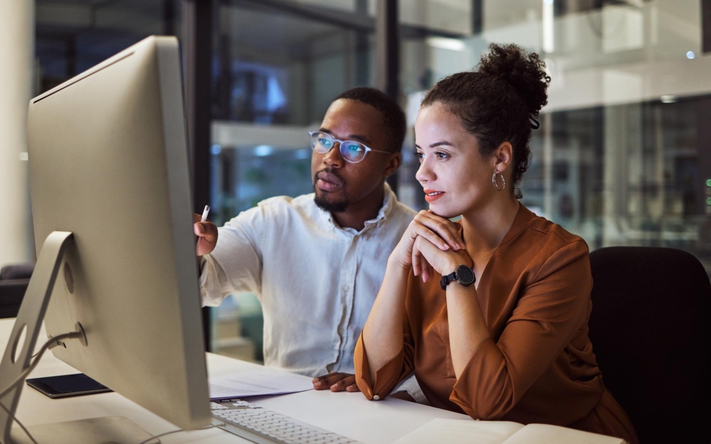 Two office workers having discussion at a computer.