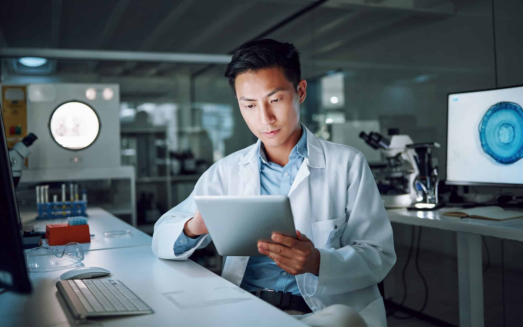 Front view of a young doctor working on a smart tablet